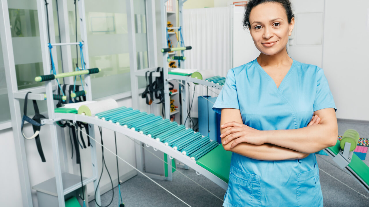 Portrait of a physiotherapist woman wearing a medical uniform standing at a rehabilitation center with arms crossed. Staff of rehab clinic