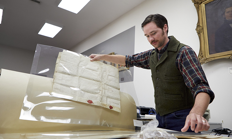 Caucasian male in office flipping through large format historical documents